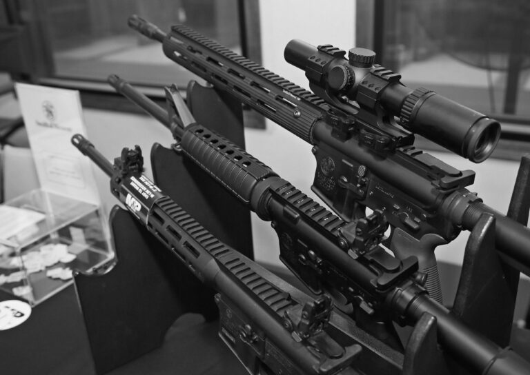 Three Smith & Wesson M&P15 rifles are on display at a firearm trade show.