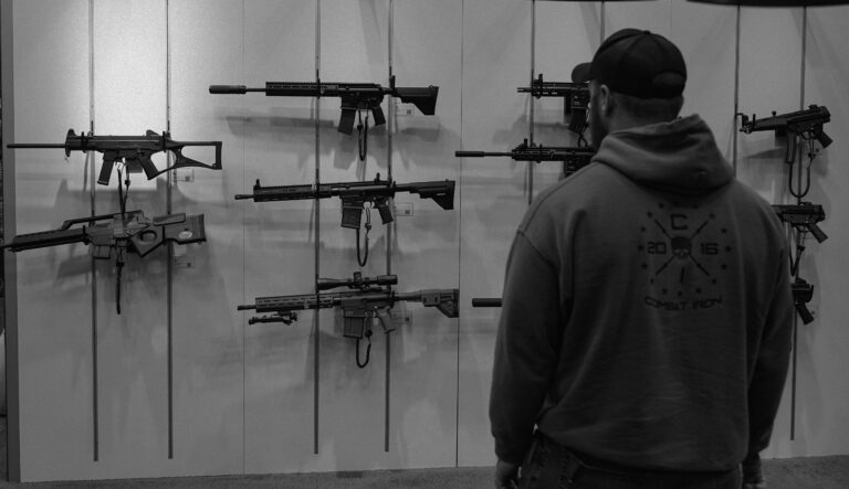 A man looks over firearms displayed at the Heckler & Koch booth during a firearms trade show.