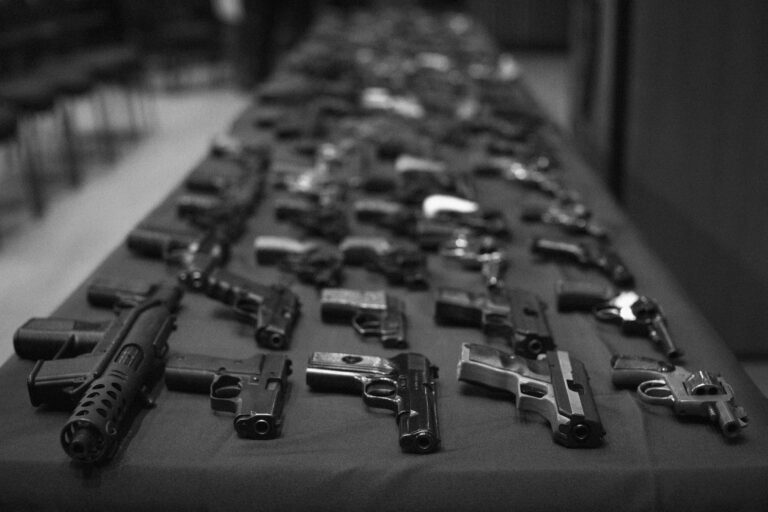 Guns recovered from trafficking investigations are displayed on a table during a press conference.
