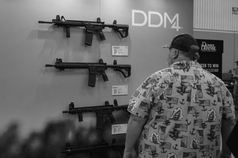 An attendee looks over AR-15s on display at the Daniel Defense booth at the 2023 NRA show in Indianapolis.