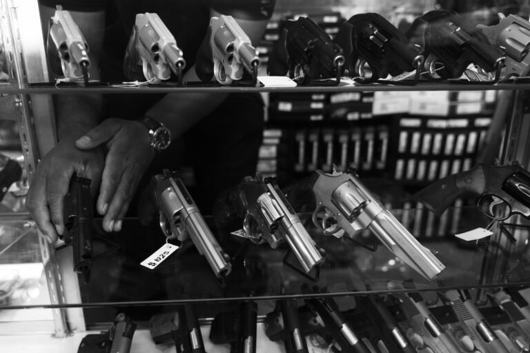 A man reaches for a revolver inside a handgun display cabinet at a gun shop in California. According to the NSSF, the ATF is ending its Demand Letter 2 program to monitor problematic gun dealers.