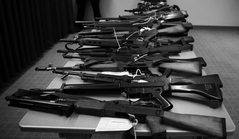 Police stand guard over guns seized from traffickers. The ATF recently changed its NICS alert policies making it harder for agents to stop trafficking attempts.
