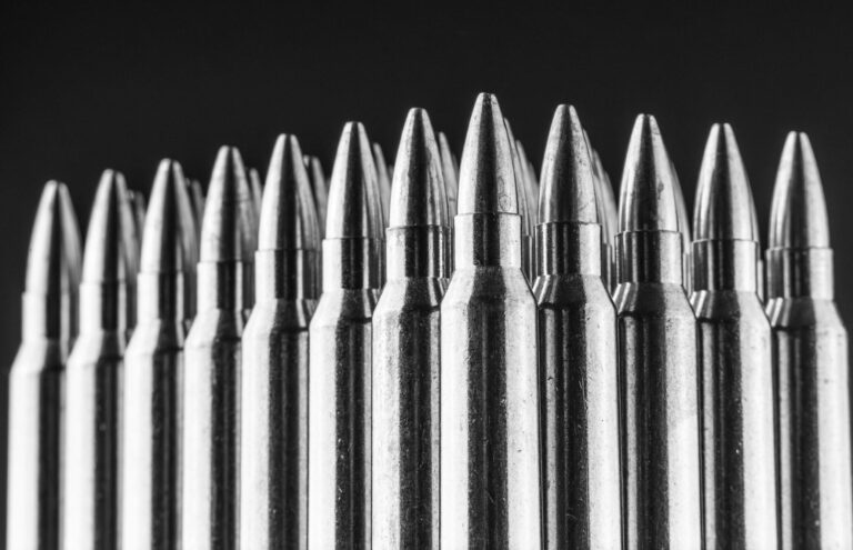 Several .223 Remington rounds are shown standing against a dark background. A New York Times investigation recently revealed that the Lake City Army Ammunition Plant produces over 30 percent of the AR-15 rounds used in crimes across the country.